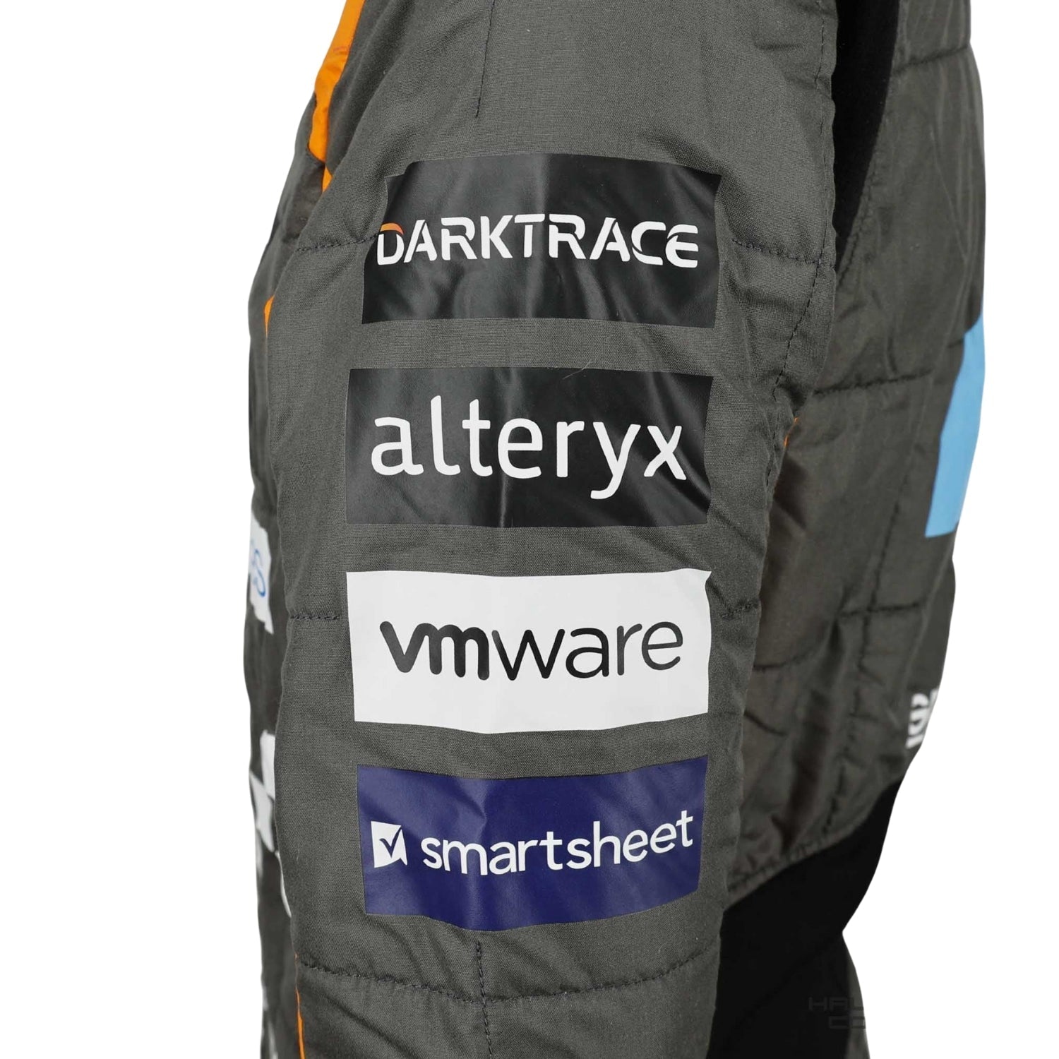 Zoomed-in look at Lando Norris’s 2023 suit featuring premium materials, high-contrast stitching, and detailed sponsor elements.